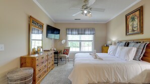 Ein Schlafzimmer mit Bett, Kommode, Stuhl und Deckenventilator.