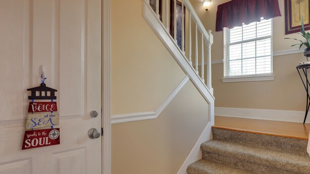 A staircase with beige walls and a wooden handrail.