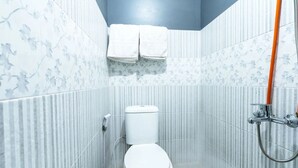 A small bathroom with a toilet, a shower, and a towel rack with two towels.