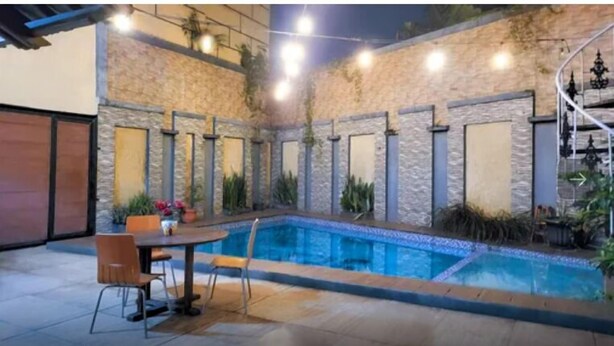 A swimming pool with stone walls and a table with chairs.