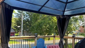 A covered outdoor deck with a table and chairs, a blue chair, and a red chair.