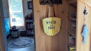 A wooden interior with a striped bag hanging, a metal bucket, and a shelf with various items.
