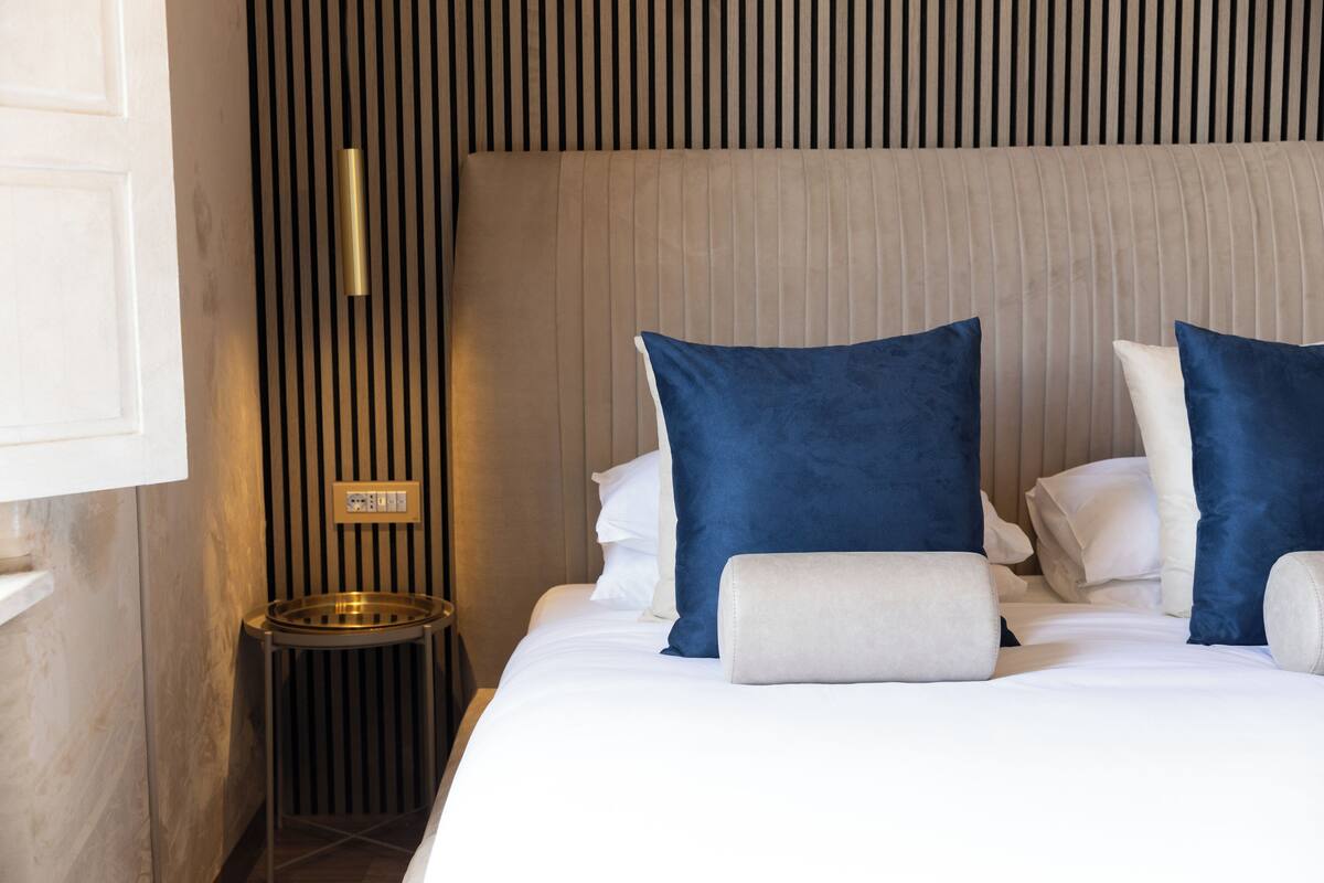 A hotel room with a bed, a bedside table, and a wall-mounted light fixture.