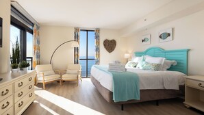 Ein Schlafzimmer mit Bett, Stuhl, Kommode und Meerblick.