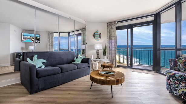Ein modernes Wohnzimmer mit einer Couch, einem Couchtisch und einem großen Fenster mit Blick auf das Meer.