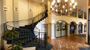Eine imposante Lobby mit Treppe, einer Kristallleuchter und einem Fliesenboden.