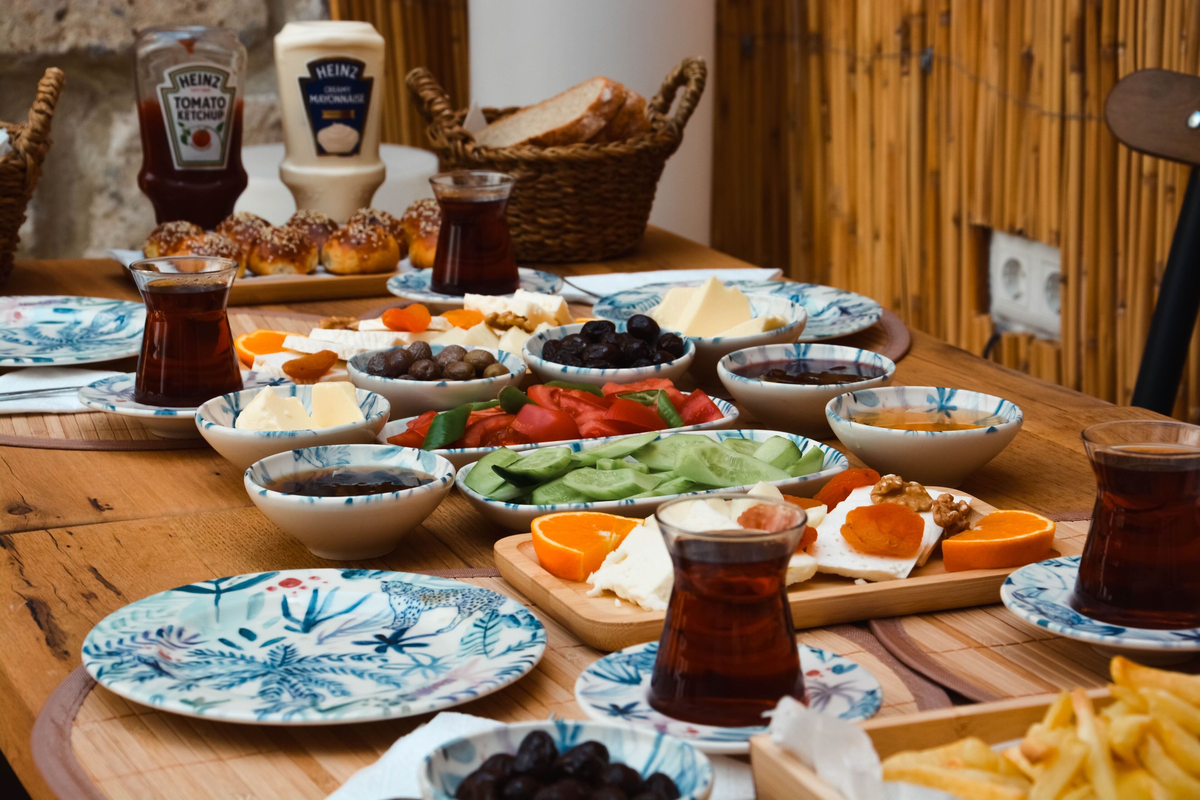 Una mesa de madera con diferentes alimentos, como queso, aceitunas y pan, además de salsas y bebidas.