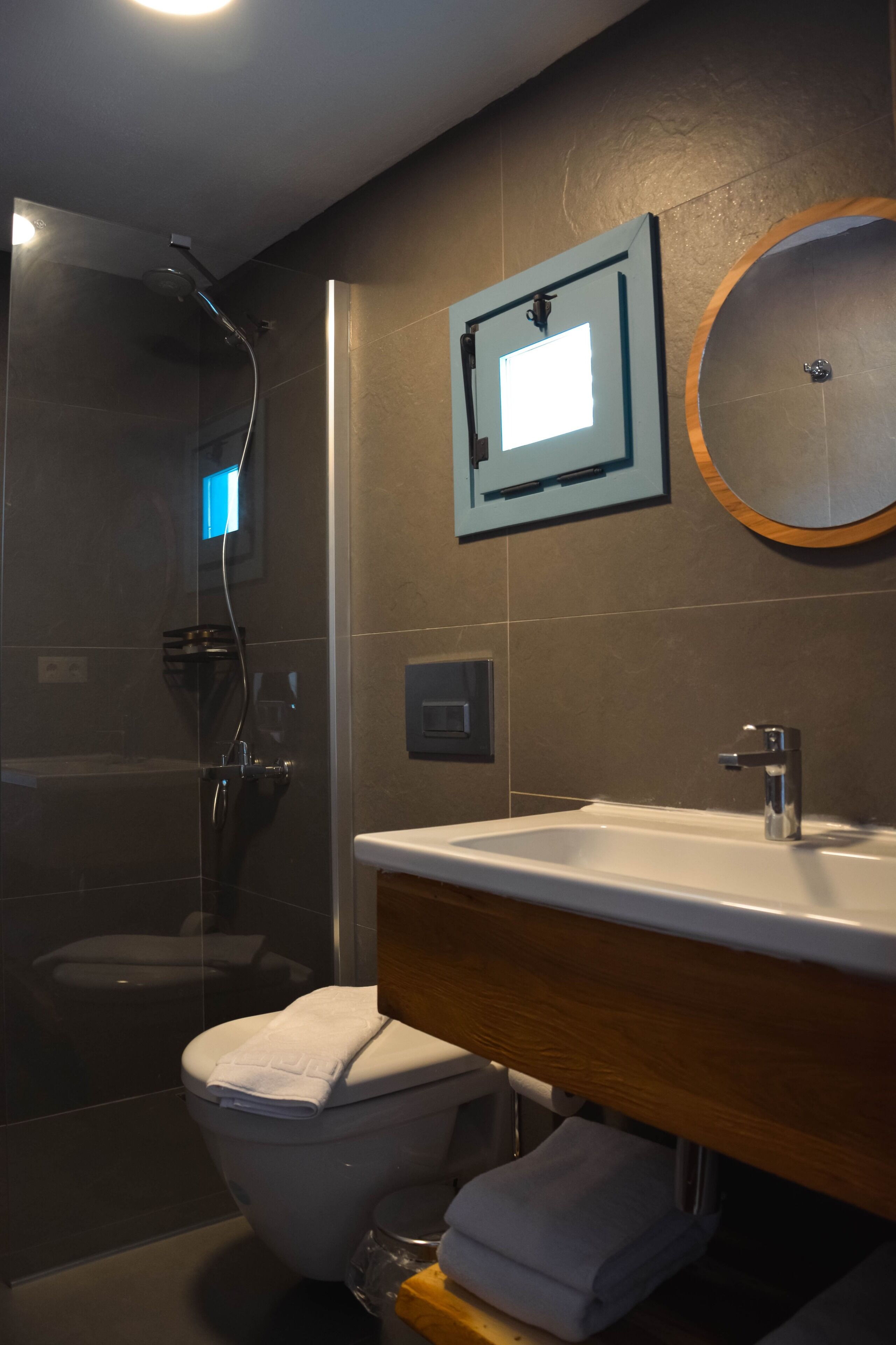 A modern bathroom with a glass-enclosed shower, a white sink, and a wooden vanity.