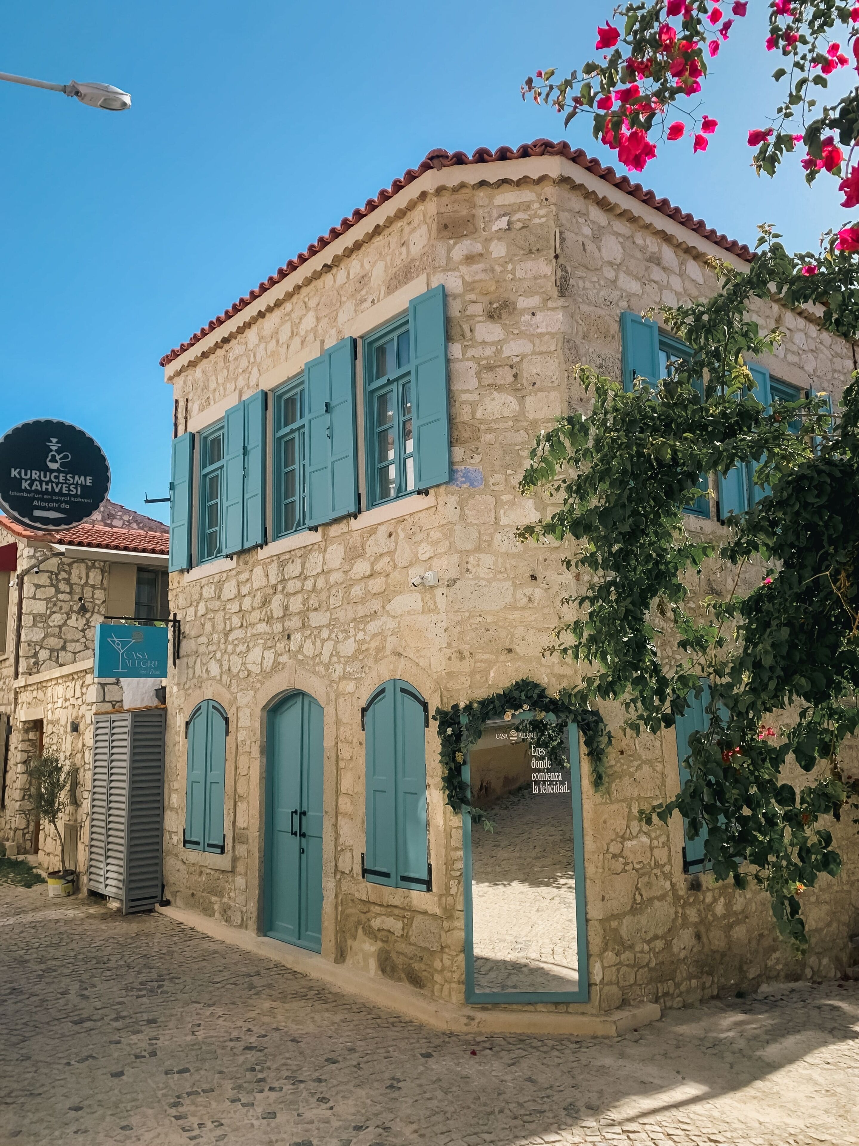 A stone building with blue shutters and a sign for "Kurucesme Kahvesi".