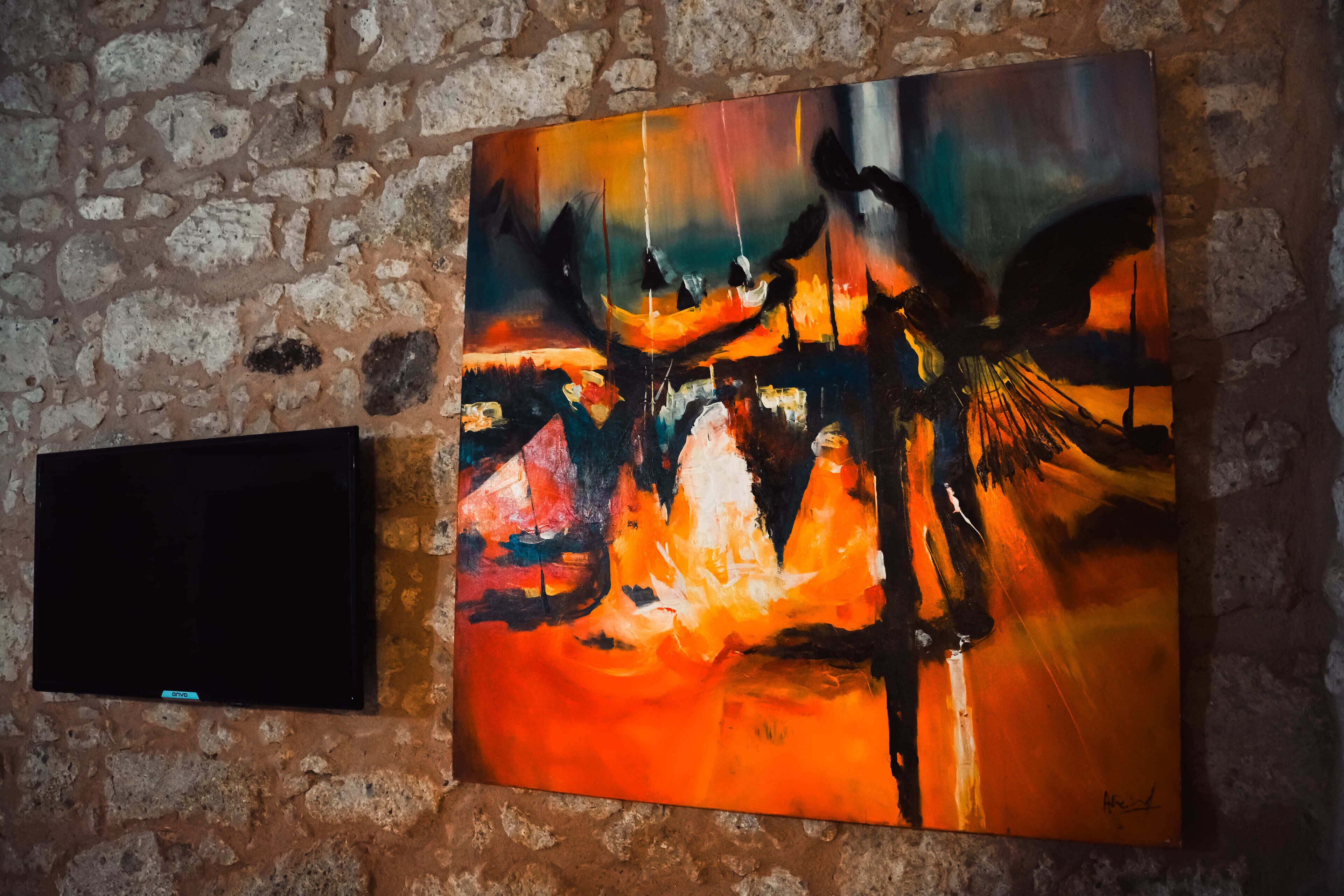 A painting on a brick wall next to a flat-screen TV.