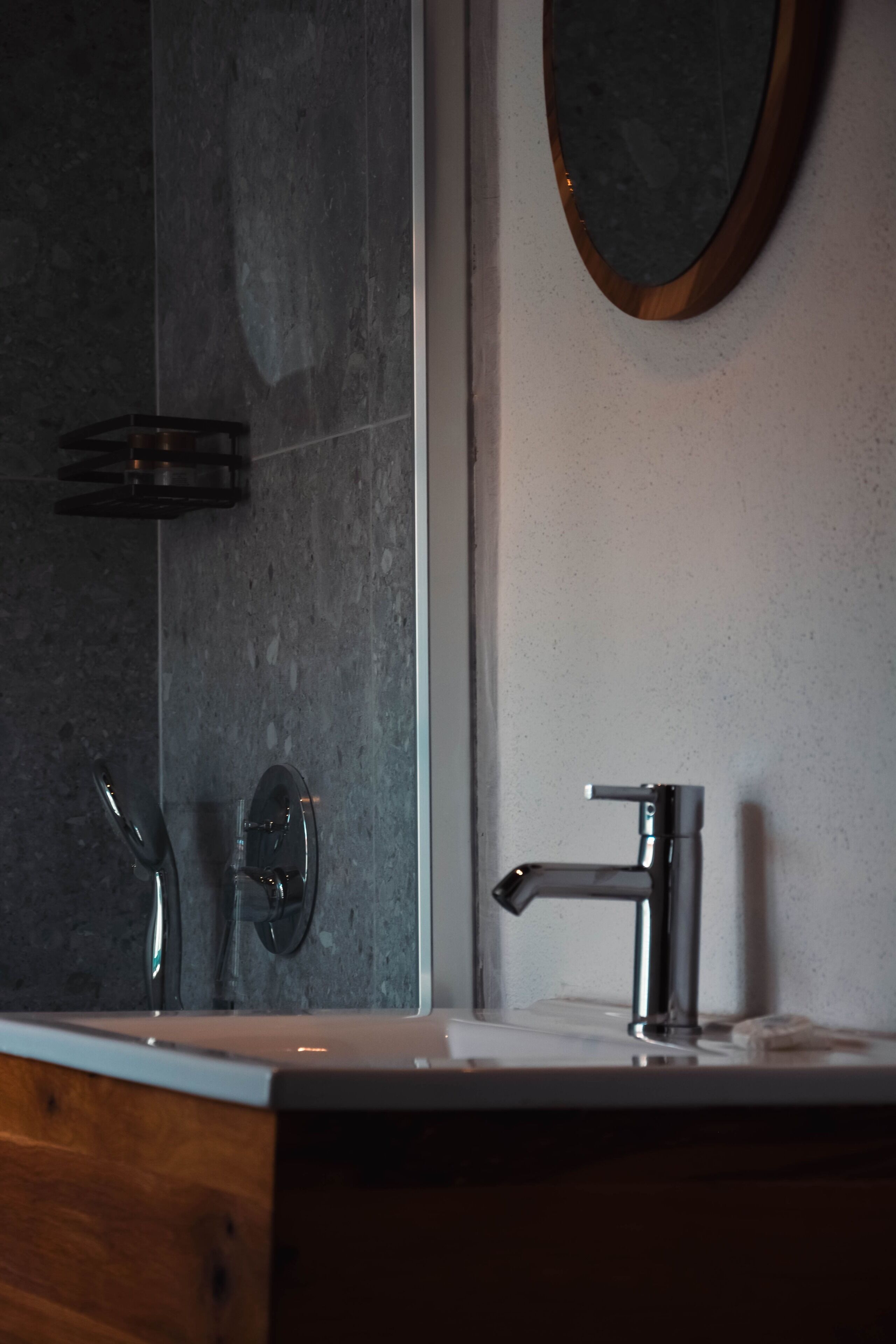A bathroom with a modern design, featuring a large mirror, a sink with a faucet, and a towel rack.