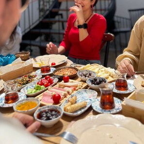 A dining table with various dishes and drinks, including a salad, cheese, and a pitcher of tea. - Casa Alegre Alaçatı (Cesme)