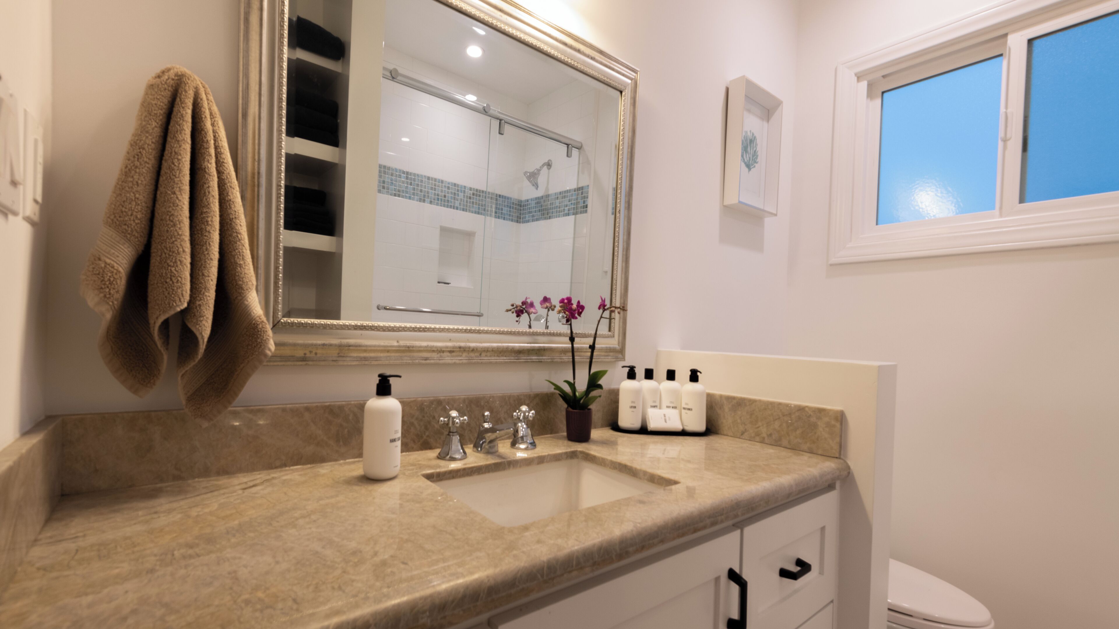 Une salle de bain avec un grand miroir, un lavabo et une fenêtre.