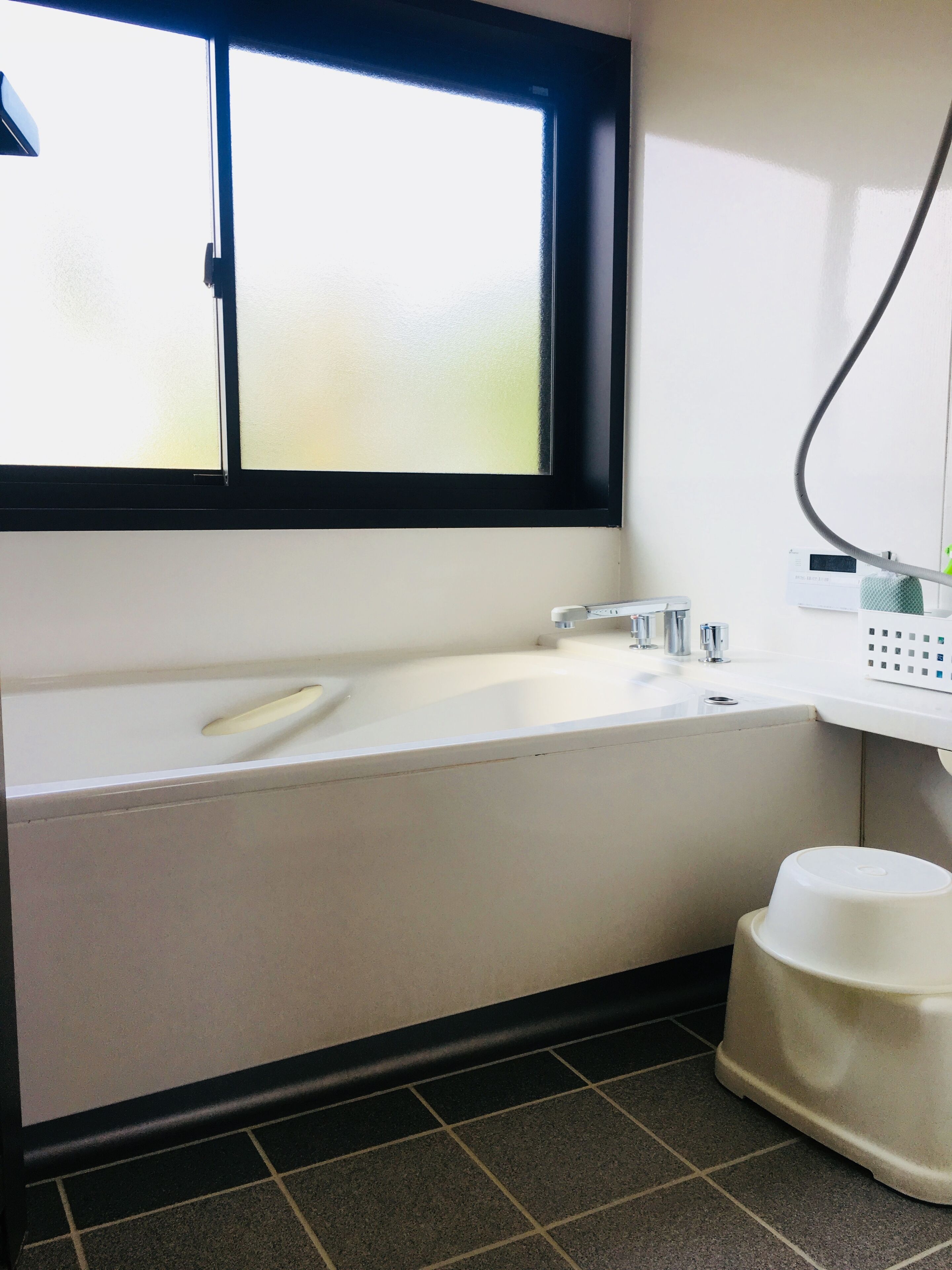 A bathroom with a white sink, a black-framed window, and a white toilet.