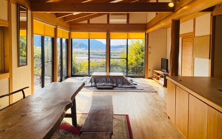 A spacious room with a large wooden table, a bench, and a TV on a wooden cabinet.