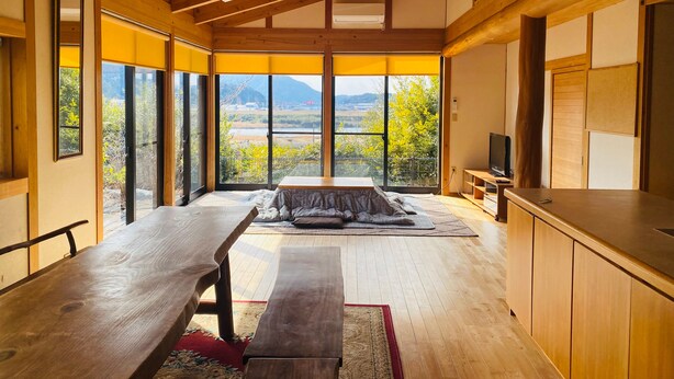 Une pièce spacieuse avec une grande table en bois, un banc et un téléviseur posé sur un meuble en bois.