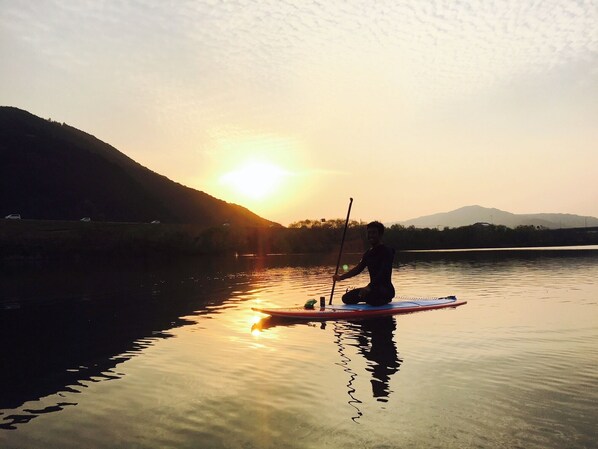 A person paddleboarding on a calm body of water during sunset. - Shimantogawa no yado yuubetei (Shimanto)