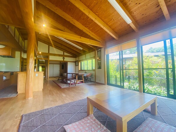 Una habitación amplia con vigas de madera, un ventanal grande y una mesa de madera.