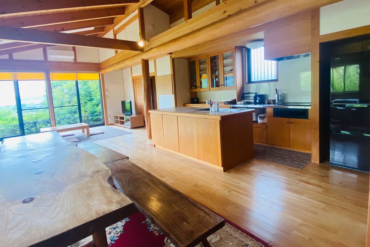 A spacious kitchen with wooden cabinets, a central island, and a large window providing a view of the outdoors.