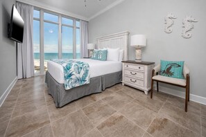 A bedroom with a bed, a nightstand, a chair, and a TV. - Phoenix Gulf Towers 1008 4 Bedroom Condo (Orange Beach)