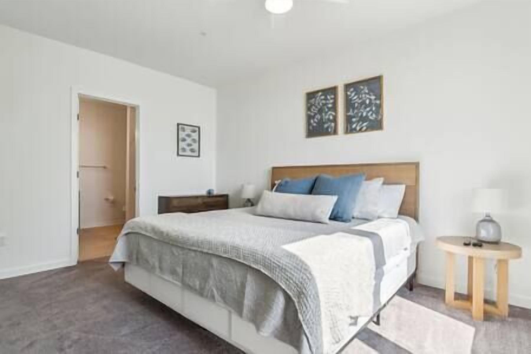 A bedroom with a bed, bedside tables, and a door.