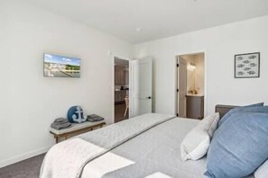 A bedroom with a bed, a nightstand, a picture on the wall, and a door leading to a bathroom. - Sail Away To (Colonial Beach)