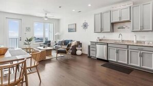 A spacious living area with a dining table, chairs, a sofa, and a view of the outdoors. - Sail Away To (Colonial Beach)