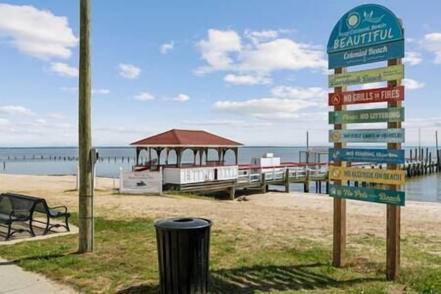A beach sign with multiple directional arrows and text, a gazebo, and a pier extending into the water.