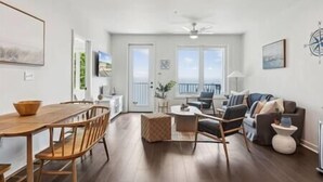 A spacious living area with a dining table and chairs, a sofa, and a balcony with a view. - Sail Away To (Colonial Beach)