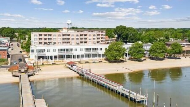 A waterfront hotel with a long pier extending into the water, a large building with multiple floors, and a clear sky. - Sail Away To (Colonial Beach)