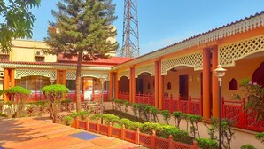 A courtyard with red railings, a tiled floor, and a building with a red roof. - Empires Joda  (Barbil)