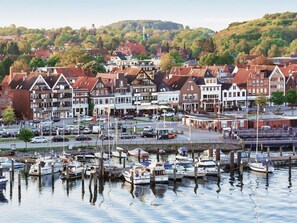 A marina with boats docked, surrounded by traditional European-style buildings with red roofs. - Holiday Vacation by the sea (Lübeck)