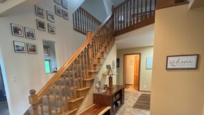 Un espacio habitable amplio con una escalera de madera, un banco y una alfombra.