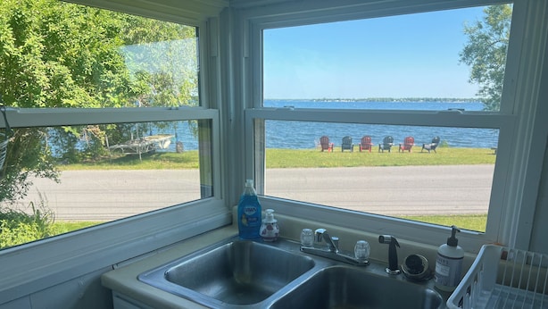 A kitchen with two sinks, a window with a view of the beach and chairs, and a bottle of Dawn dish soap. - Lake Ontario getaway 30 mins from Alexandria Bay and the famous Bolt Castle. (Dexter)