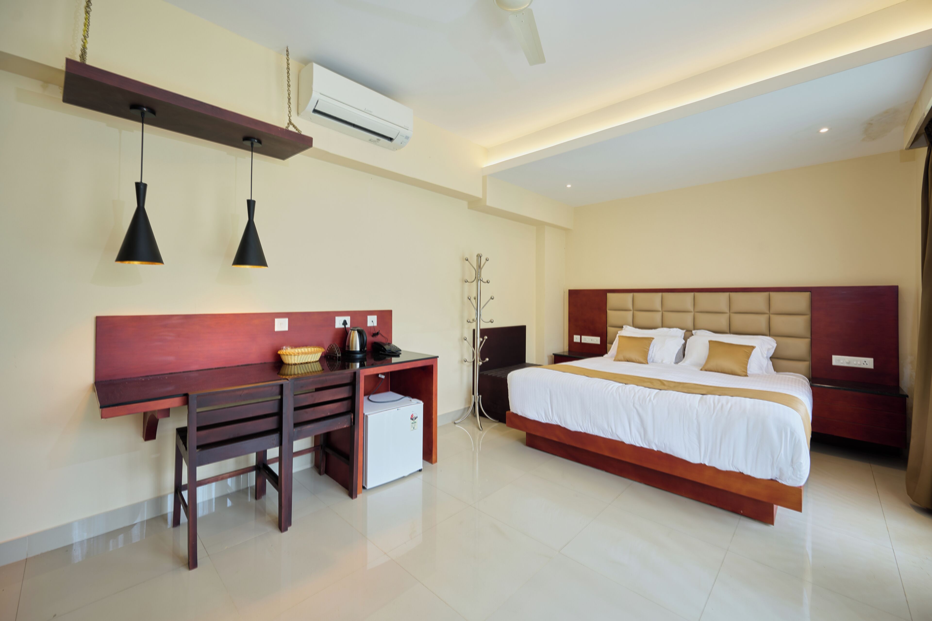 A hotel room with a bed, desk, and chair, an air conditioner, and a ceiling fan.