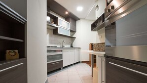 Une cuisine moderne dotée d’appareils électroménagers en acier inoxydable, de meubles blancs et d’un sol carrelé.