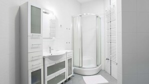 Une salle de bain moderne avec une douche à parois de verre, des meubles blancs et un grand miroir.