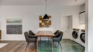 A modern kitchen with a built-in washer and dryer, a wooden dining table with four chairs, and a pendant light above. - Welcome to “Chateau Sherbrooke's” loft: an historic gem in Downtown Montreal. (Montréal)