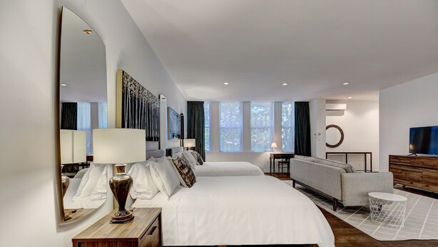 A modern hotel room with a large bed, a sofa, a desk, and a large mirror. - Welcome to “Chateau Sherbrooke's” loft: an historic gem in Downtown Montreal. (Montréal)