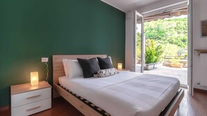 Ein Schlafzimmer mit Bett, Nachttischen und Blick auf Grün.