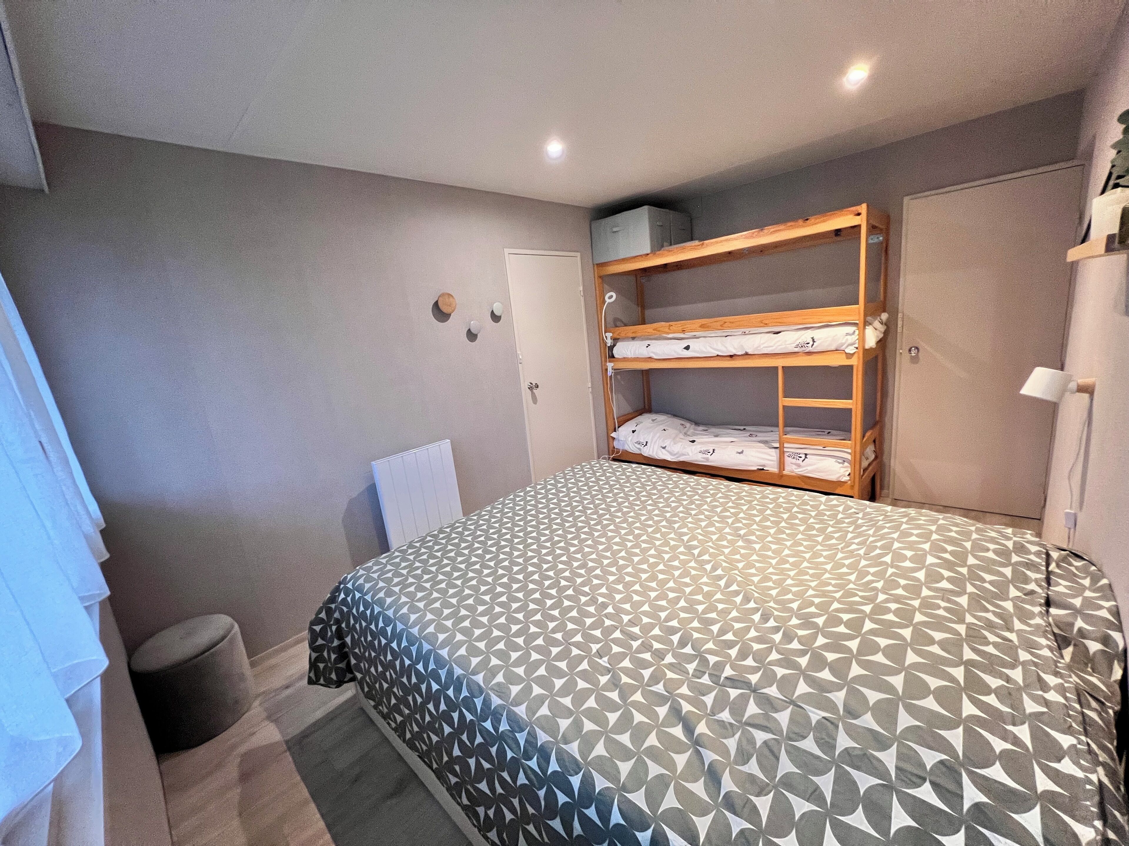 Ein Schlafzimmer mit Etagenbett, Nachttisch, Heizkörper und Kleiderschrank.