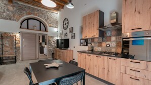 Eine moderne Küche mit Holzschränken, einer Steinwand und einem Essbereich mit Tisch und Stühlen.