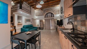 Eine moderne Küche mit Steinwand, Holzschränken und einem Essbereich mit Tisch und Stühlen.