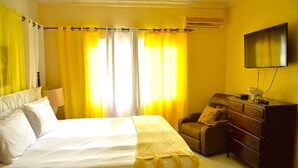 Una habitación de hotel con cama, una silla, cómoda y televisión.