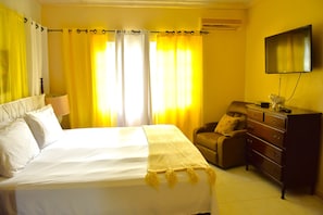 Una camera d'albergo con un letto, una sedia, una cassettiera e una televisione.