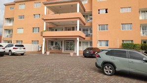 Un edificio de varios pisos con techo plano, balcones y vestíbulo cubierto.