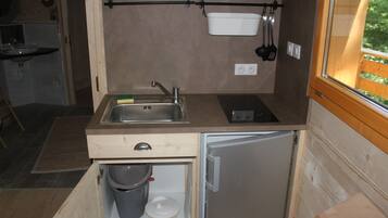 A compact kitchen with a sink, a small refrigerator, and a wooden countertop.