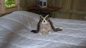 A plush owl toy on a bed with white bedding.