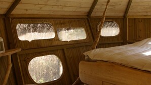 A wooden attic bedroom with a bed, a table, and two windows. - Le Parc de la Belle (Magné)