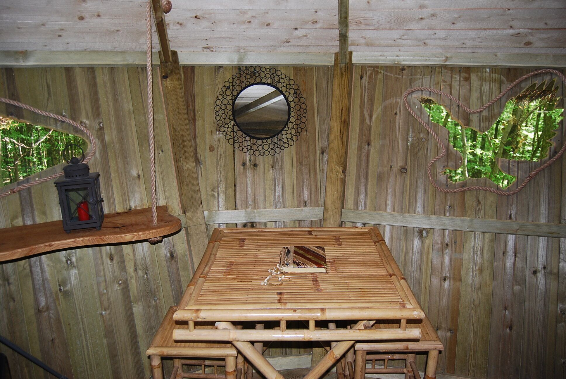 Una habitación rústica de madera con una mesa, un farol y espejos decorativos.